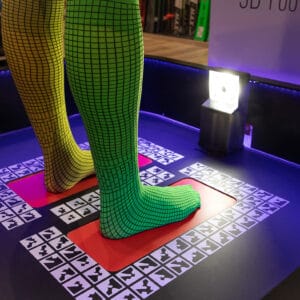 A person wearing yellow and green socks with square pattern on a 3D scanner